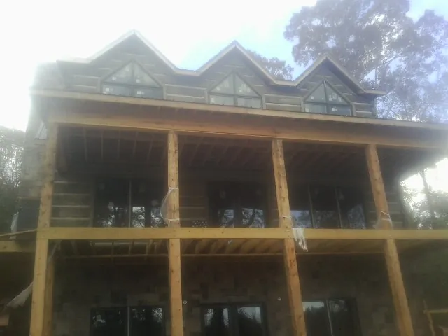 Dormers and porch framing on a large log home under construction — Roof Coating work by our crew in Toledo