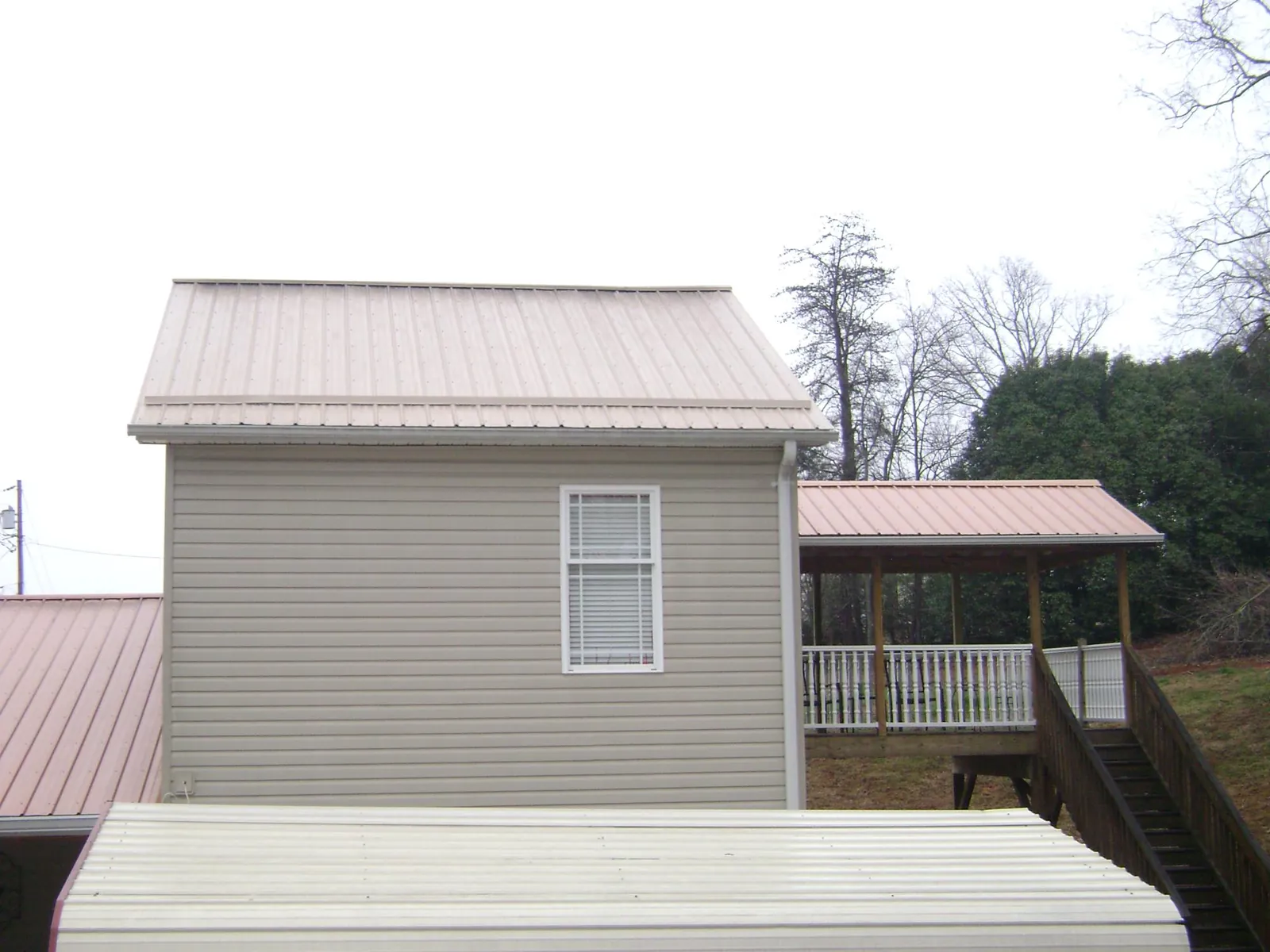 Tan metal roofs on a two story addition and attached porch, from a Roof Replacement job in Toledo