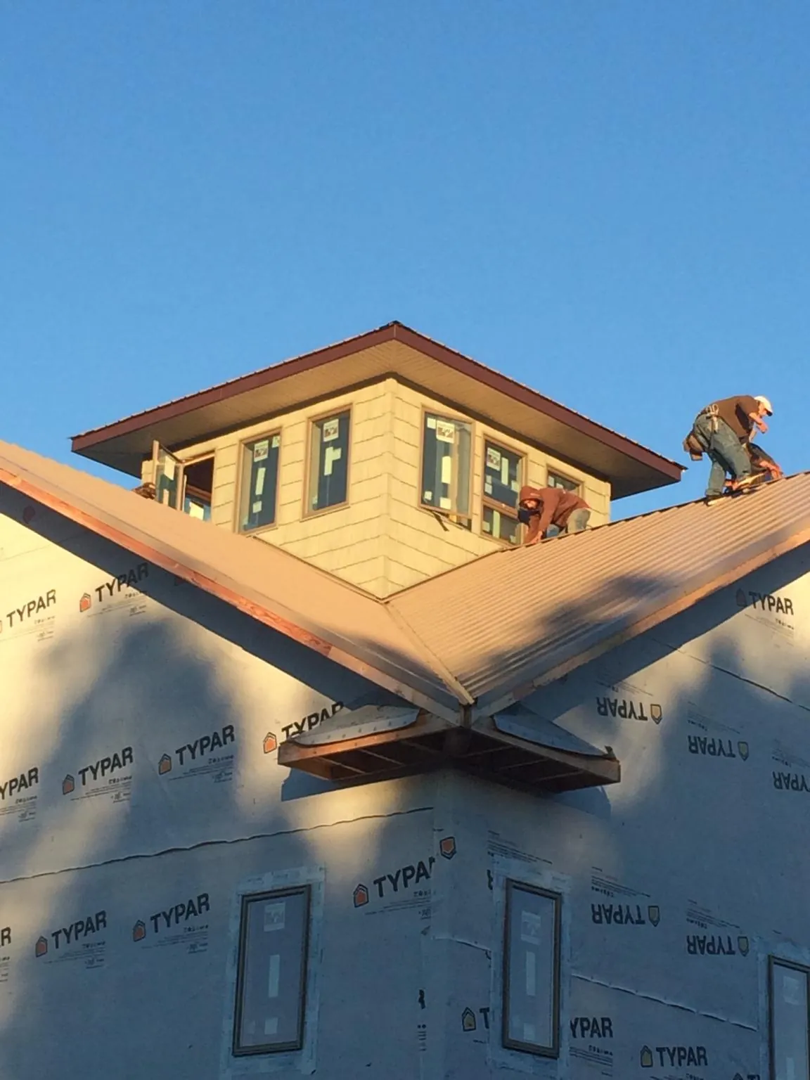 Roofers working around a rooftop cupola on a new metal roof at sunset — Roof Waterproofing in Toledo by Roofing Brothers